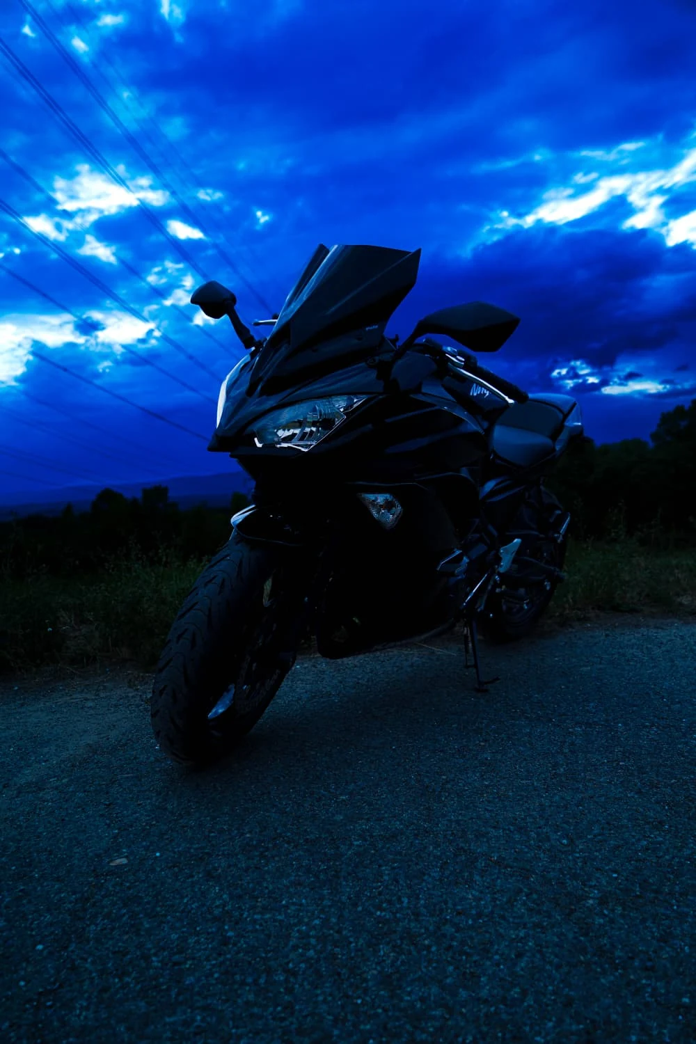 Plan large : la moto au bord de la route, sous les nuages.