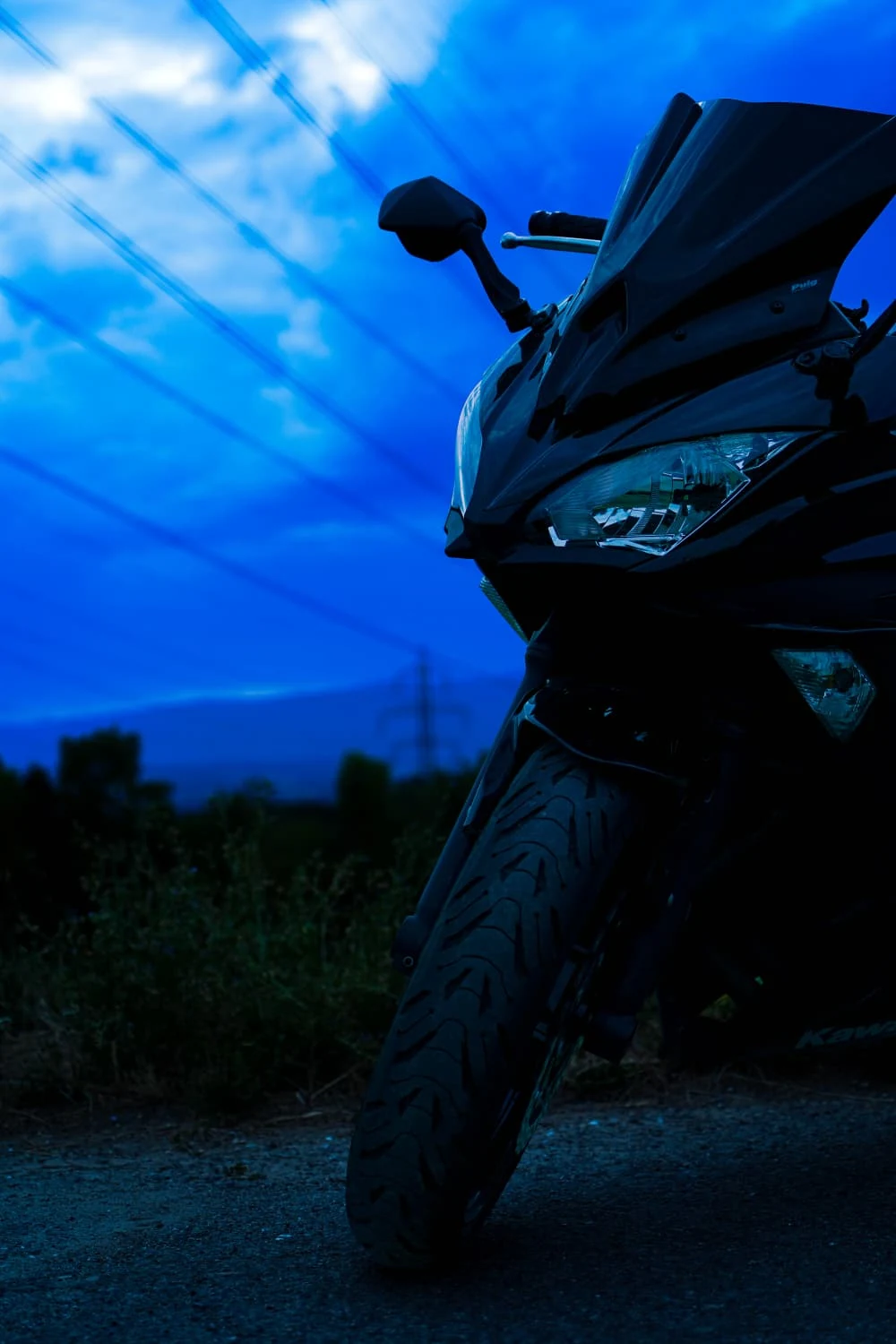 Contre-plongée sur l'avant de la moto, le phare et le rétroviseur.
